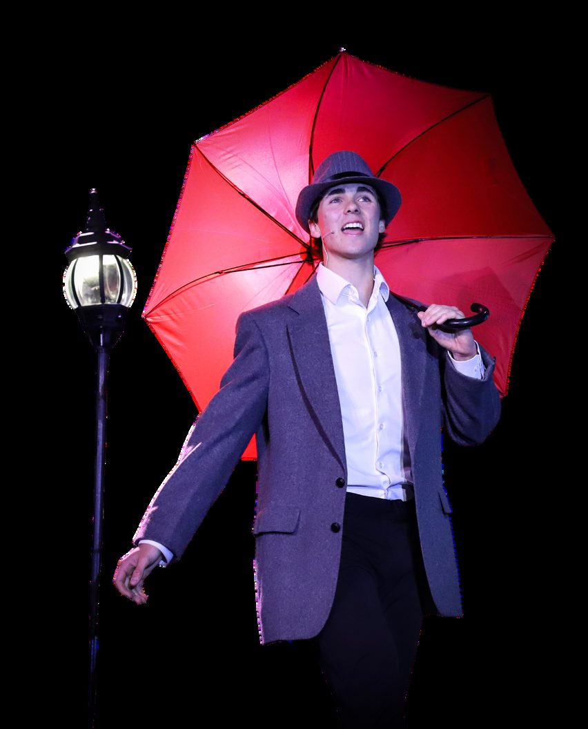 A student performing under a red umbrella in a spotlight