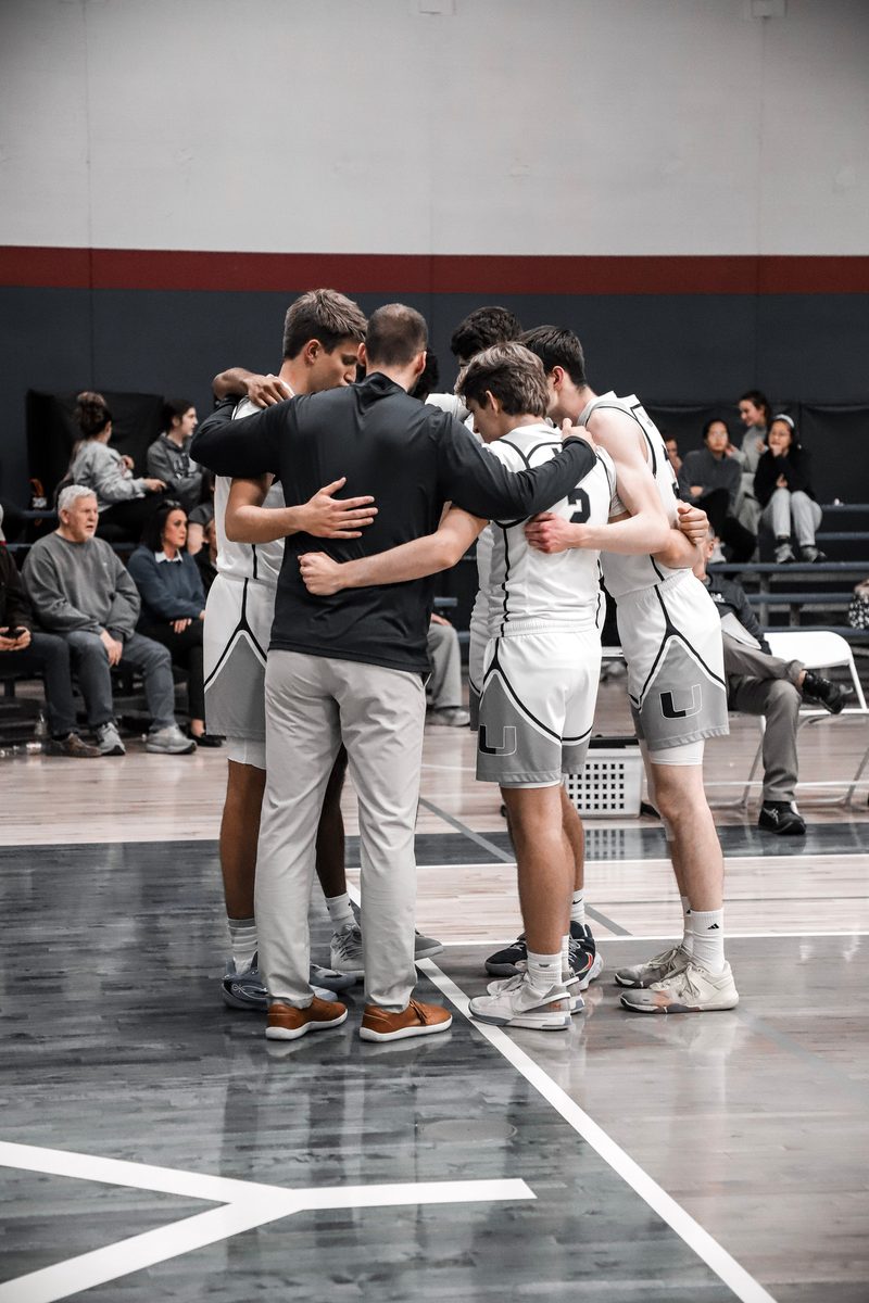 Coach Fisher with the boys basketball team in a huddle