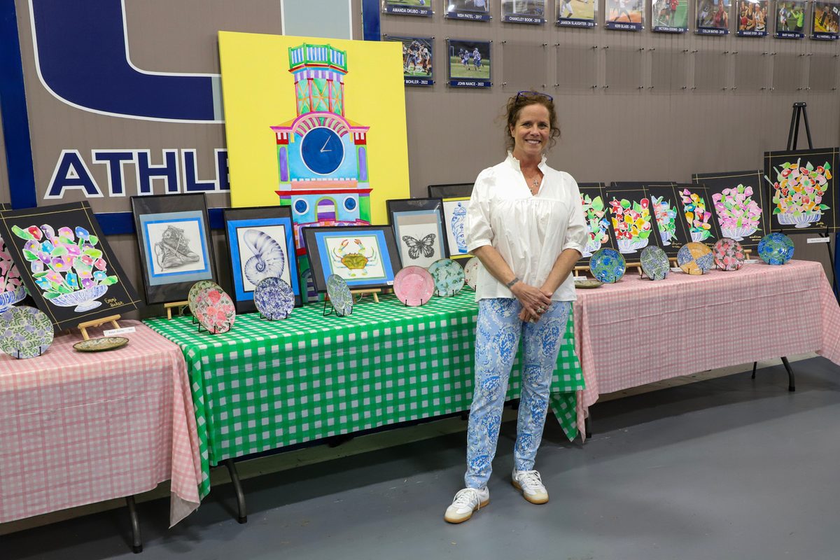 Mrs. Lily beside a table of student artwork