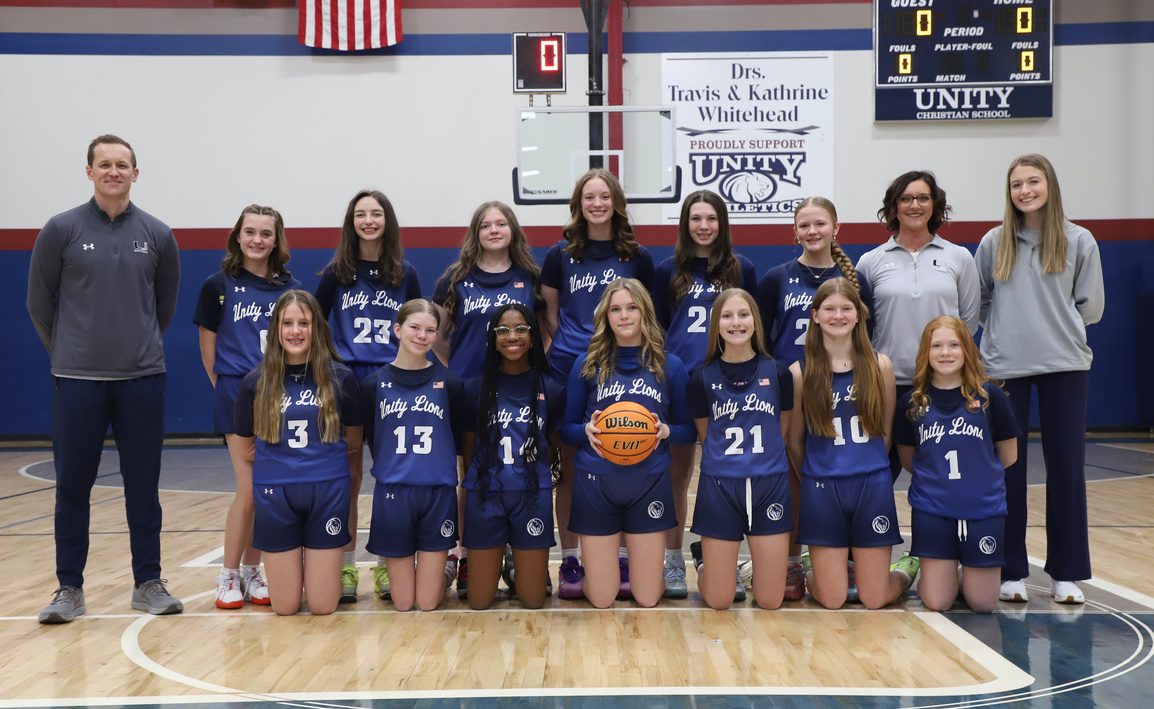 The middle school girls basketball team with their championship banner